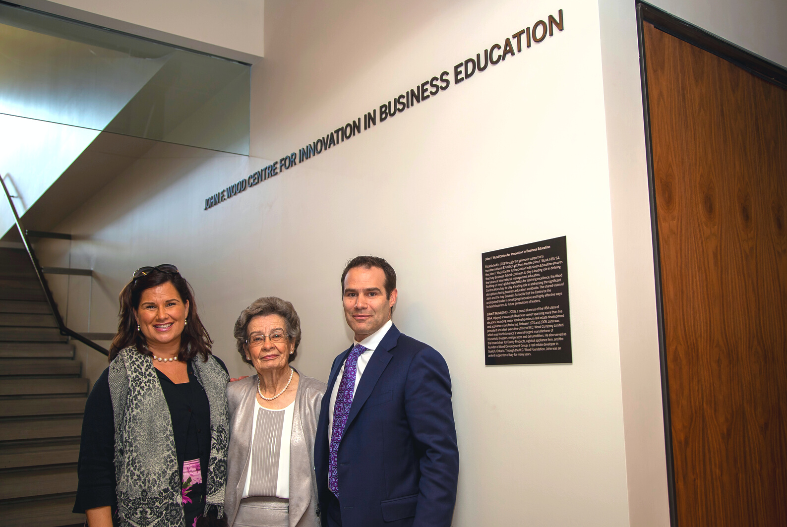 Barbara Wood stands in the middle of her children Susan and David under the "John F. Wood Centre for Innovation in Business Education" signage in the Ivey Building