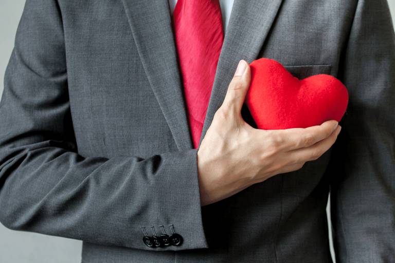 Businessman holding plush heart over chest